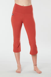 Woman's lower half facing forward of her body showing cayenne colored organic cotton Moana Capri yoga pants