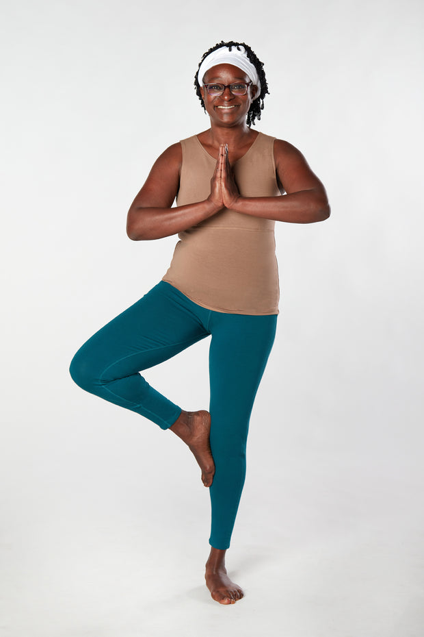 Woman facing forward smiling doing tree pose with teal organic cotton Luana Legging yoga pants