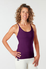 Woman facing forward smiling with her hand on her hip wearing a honeysuckle colored organic cotton Mohala Camisole yoga shirt