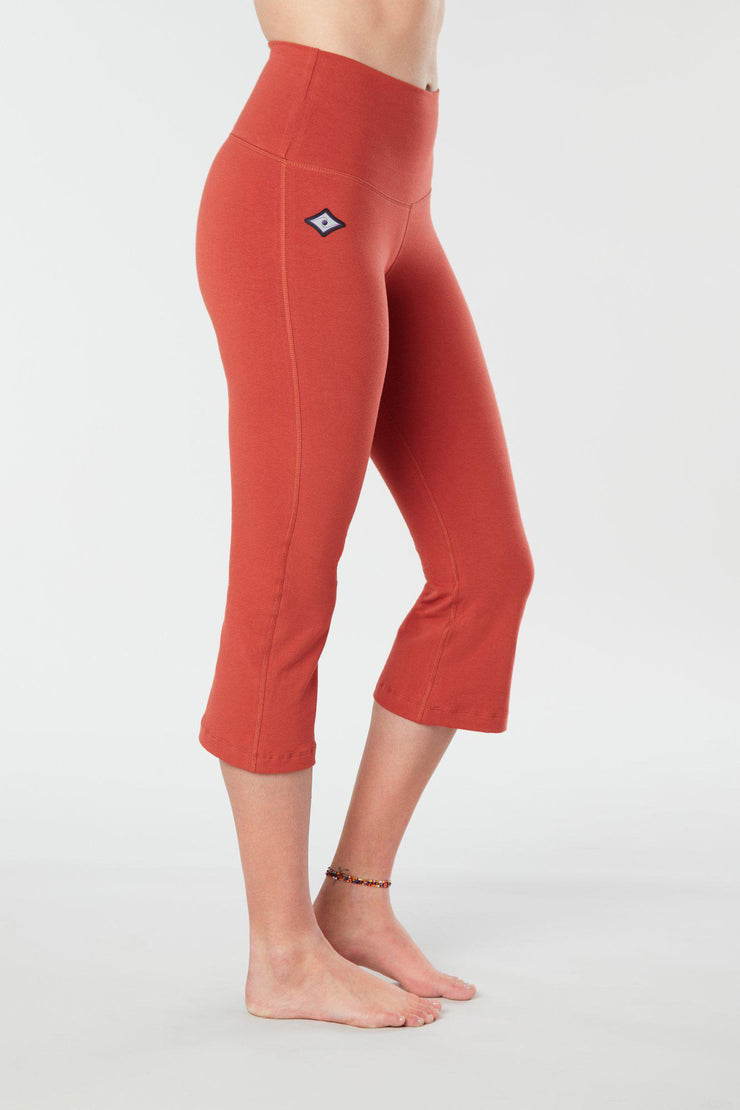 Woman's lower half facing sideways of her body showing cayenne colored organic cotton Moana Capri yoga pants