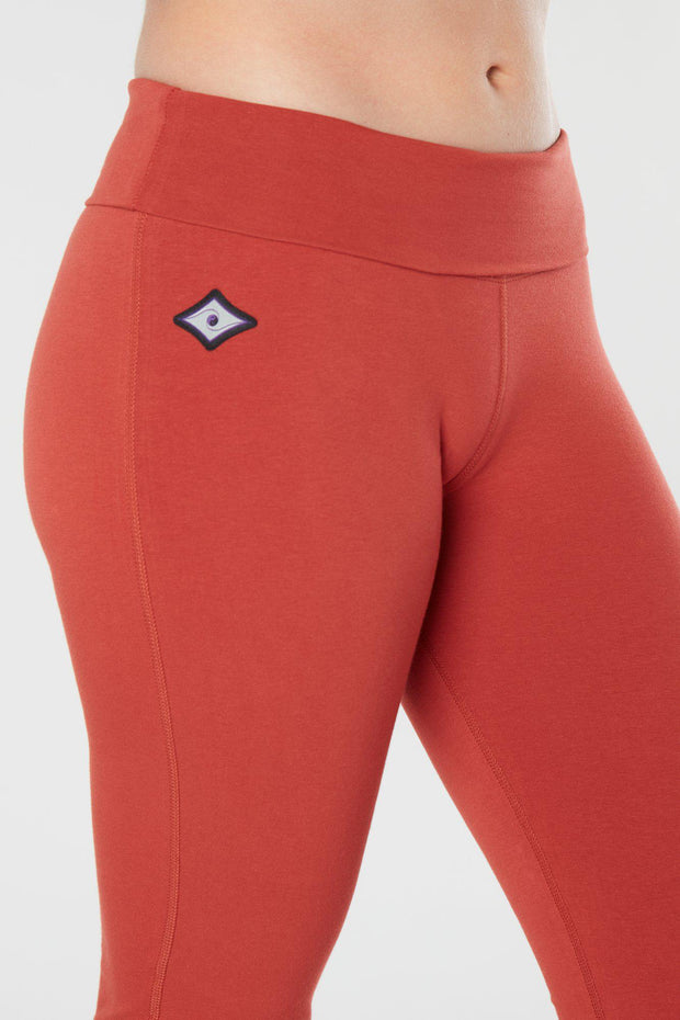 Closer look at the woman's lower half facing forward of her body showing cayenne colored organic cotton Moana Capri yoga pants
