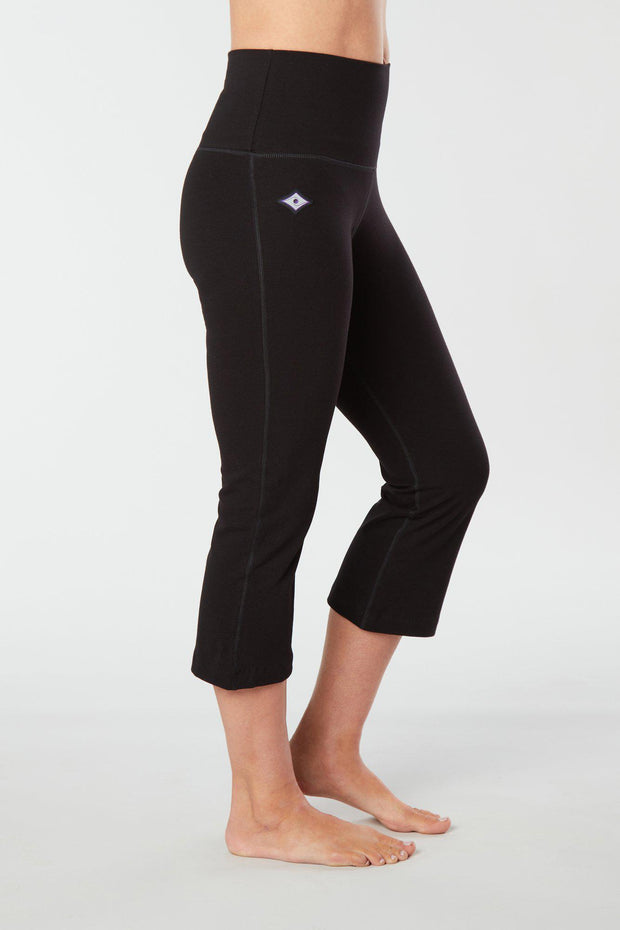 Woman's lower half facing sideways of her body showing black colored organic cotton Moana Capri yoga pants