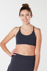 Women looking forward smiling with hand on hip wearing black Kahe Skirt and sports bra.