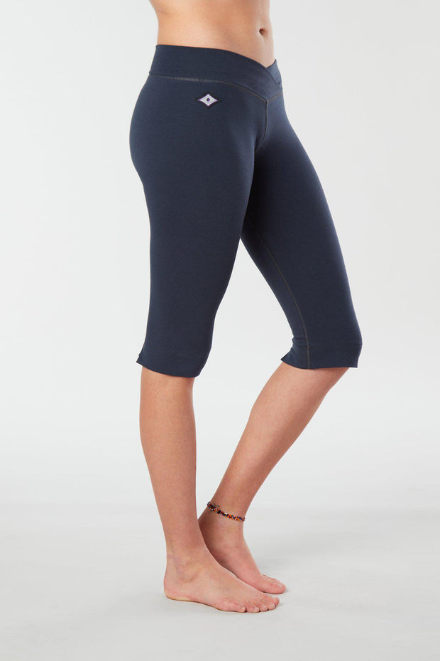 Women lower body showing legs and feet facing sideways wearing dark blue colored organic cotton Pono Capri yoga pants