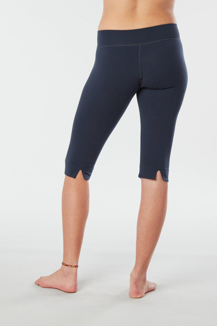 Women lower body showing legs and feet facing backwards wearing dark blue colored organic cotton Pono Capri yoga pants