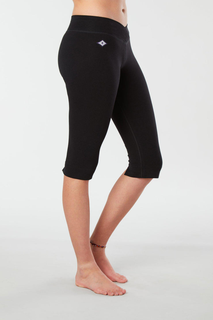 Women lower body showing legs and feet facing sideways wearing black colored organic cotton Pono Capri yoga pants