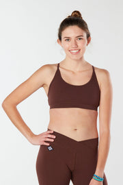 Woman smiling facing forward with hand on hip wearing a brown colored organic cotton Maha Top