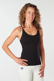 Woman facing forward smiling with her hand on her hip wearing a black colored organic cotton Mohala Camisole yoga shirt