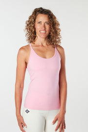 Woman facing forward smiling with her hand on her hip wearing a pink cupcake colored organic cotton Mohala Camisole yoga shirt