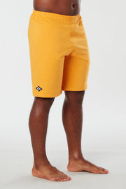 Front facing mans lower half of body wearing yellow colored organic cotton Mana yoga shorts