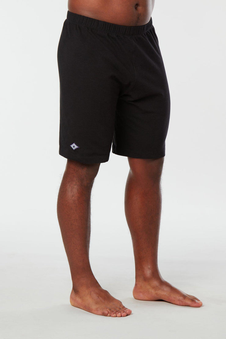 Front facing mans lower half of body wearing black colored organic cotton Mana yoga shorts
