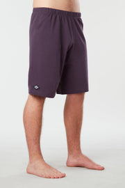 Front facing mans lower half of body wearing purple colored organic cotton Mana yoga shorts