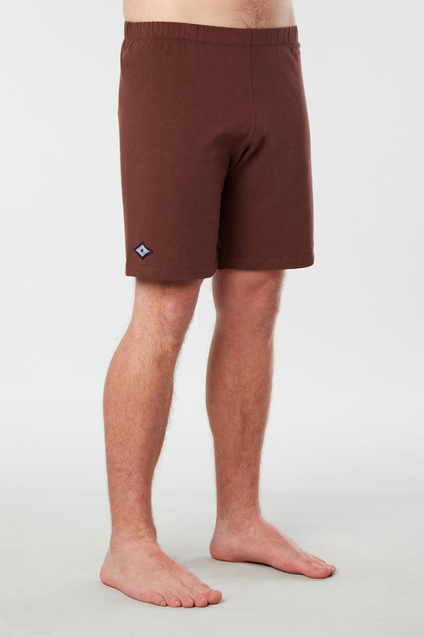 Front facing mans lower half of body wearing brown colored organic cotton Mana yoga shorts