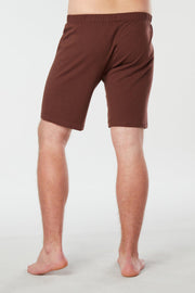 Back of mans lower half of body wearing brown colored organic cotton Mana yoga shorts