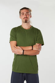 Man facing forward with arms folding wearing olive green colored organic cotton Mana Tee yoga shirt