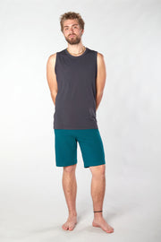 Bearded man standing facing forward with arms behind his back wearing gray yoga shirt and teal colored organic cotton Mana shorts