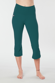 Woman's lower half facing forward of her body showing deep teal colored organic cotton Moana Capri yoga pants
