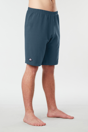 Front facing mans lower half of body wearing blue colored organic cotton Mana yoga shorts
