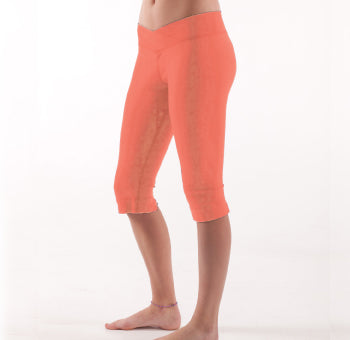 Women lower body showing legs and feet facing sideways wearing peach colored organic cotton Pono Capri yoga pants