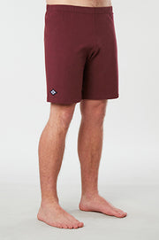 Front facing mans lower half of body wearing maroon colored organic cotton Mana yoga shorts