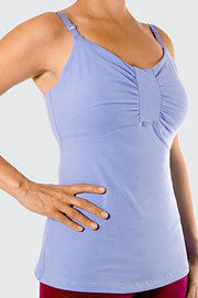 Woman torso facing forward with hands on hips wearing light blue organic cotton Lilly Top